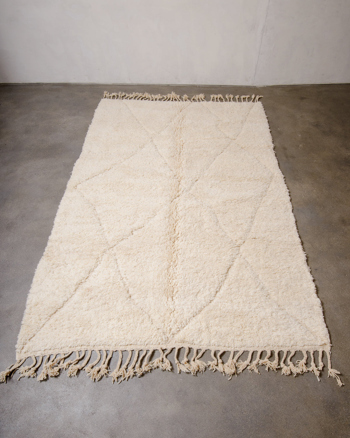 Berberlin Beniourain rug made of cream wool laying flat on concrete floor.